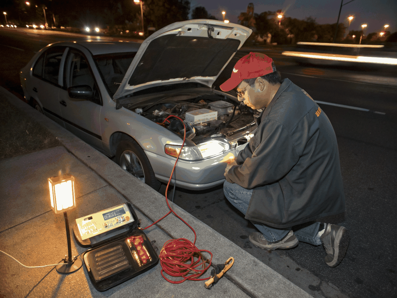 Auto electrical technician testing vehicle wiring loom with a multimeter inside mobile workshop van
